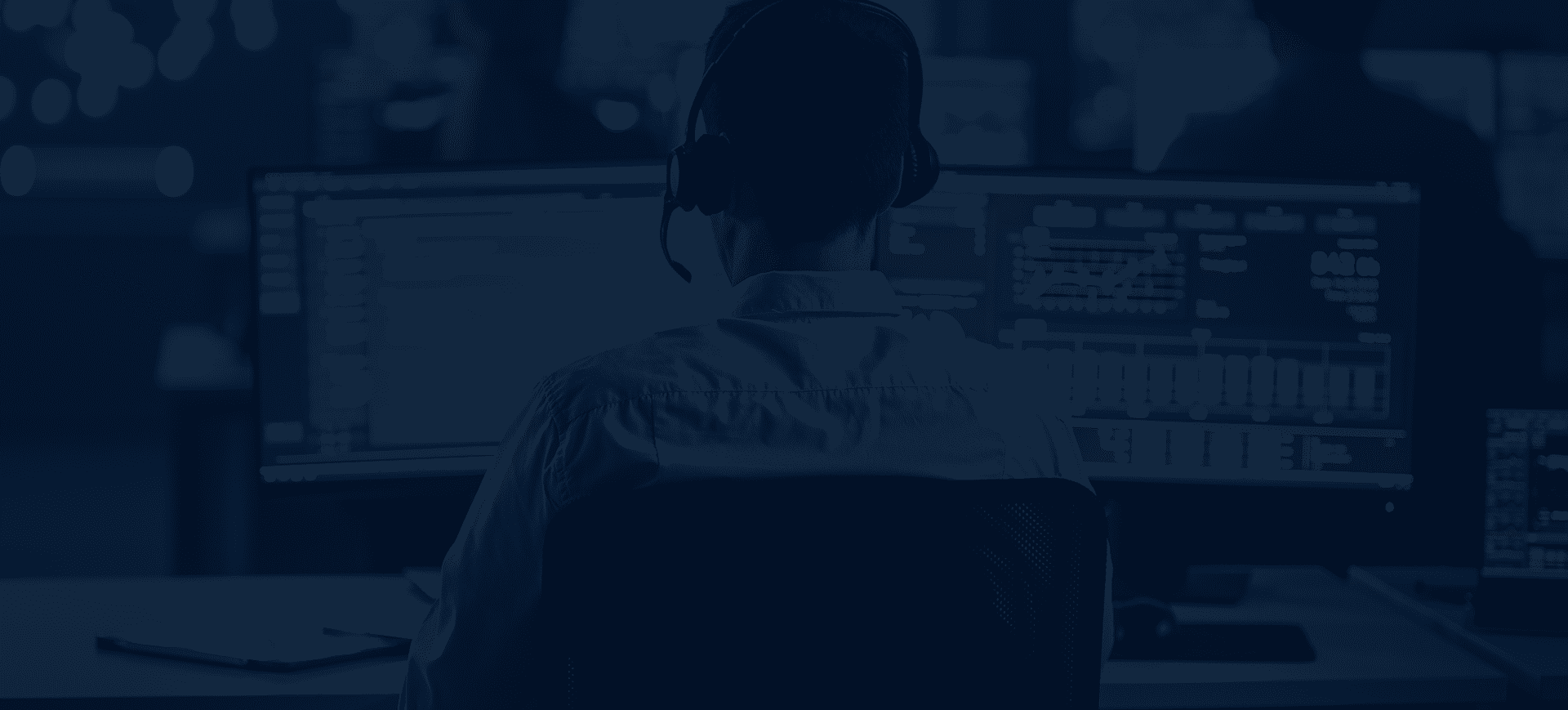 background image of IT support technician at desk with PC screens
