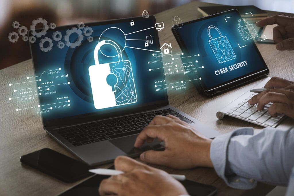 A laptop screen with a cybersecurity icon and a tablet with a lock on it.