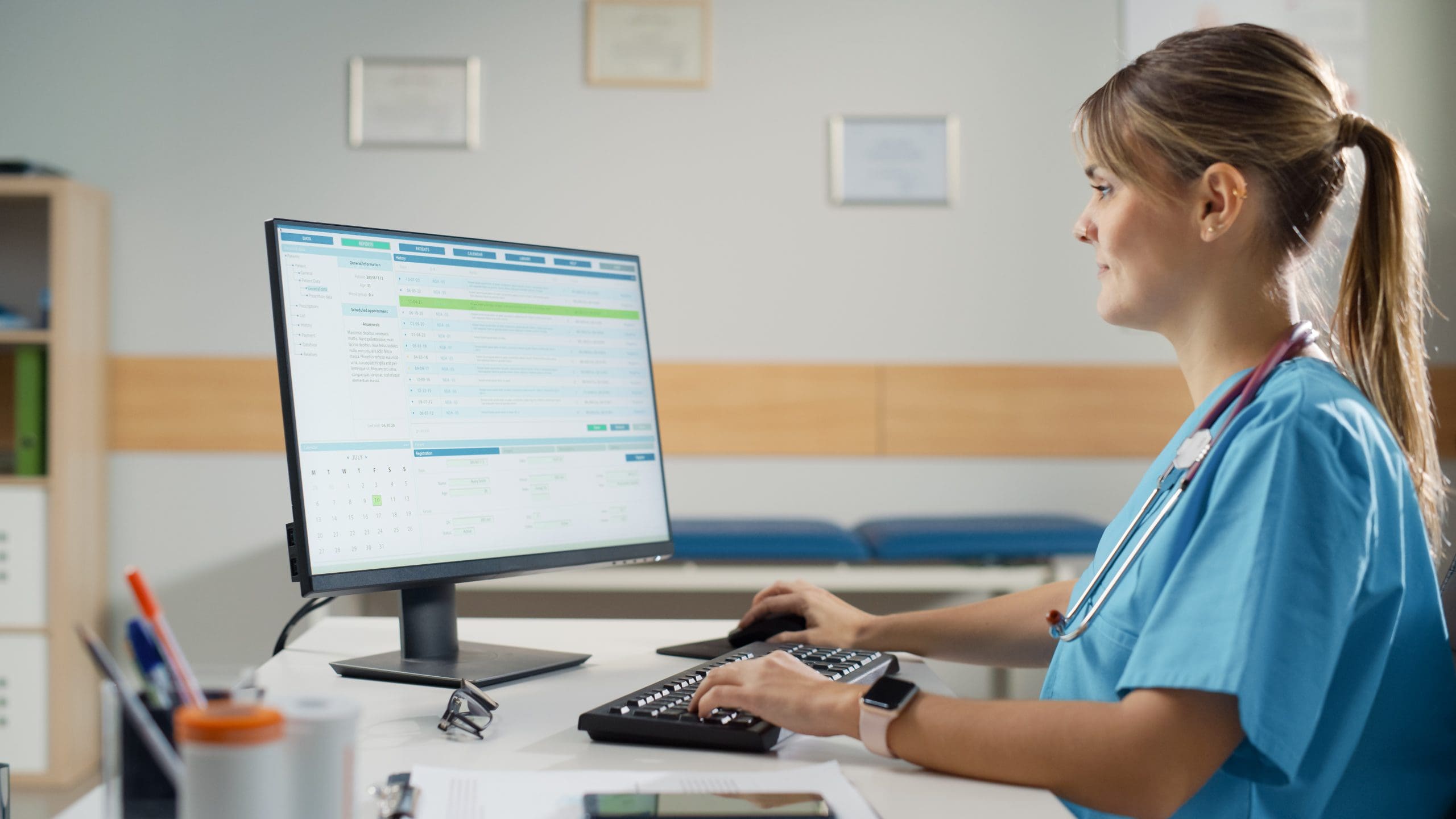 A healthcare nurse smiles as she works on a computer