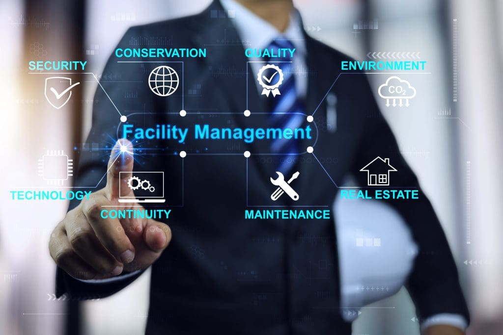 Businessman or engineering manager with white helmet pointing to facility management word map