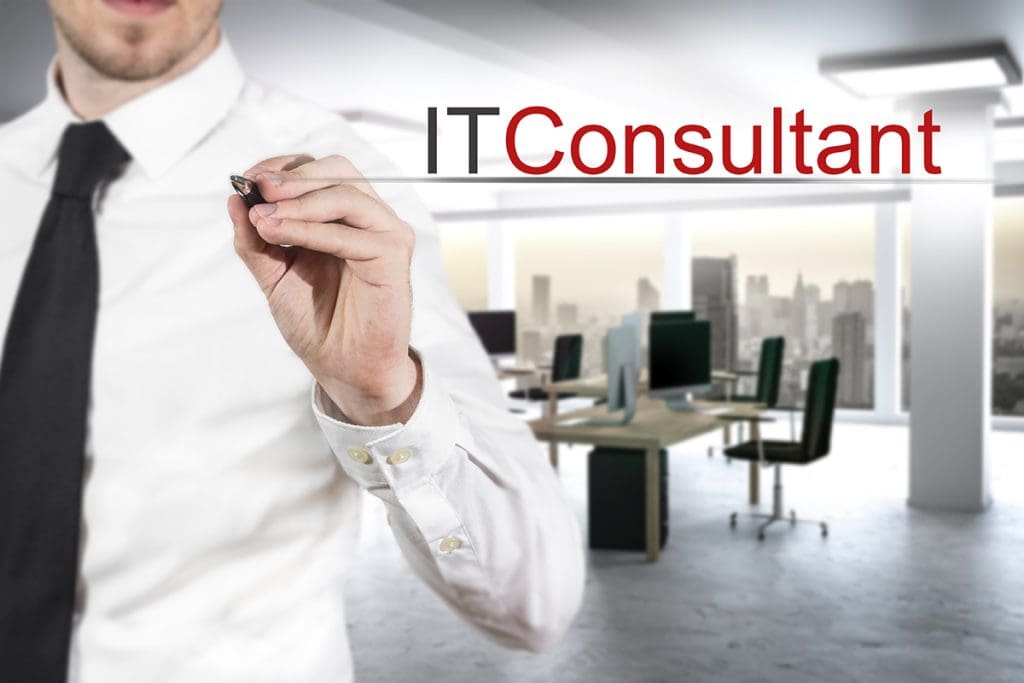 A man in a business suit underlining the words IT Consultant on a white board.