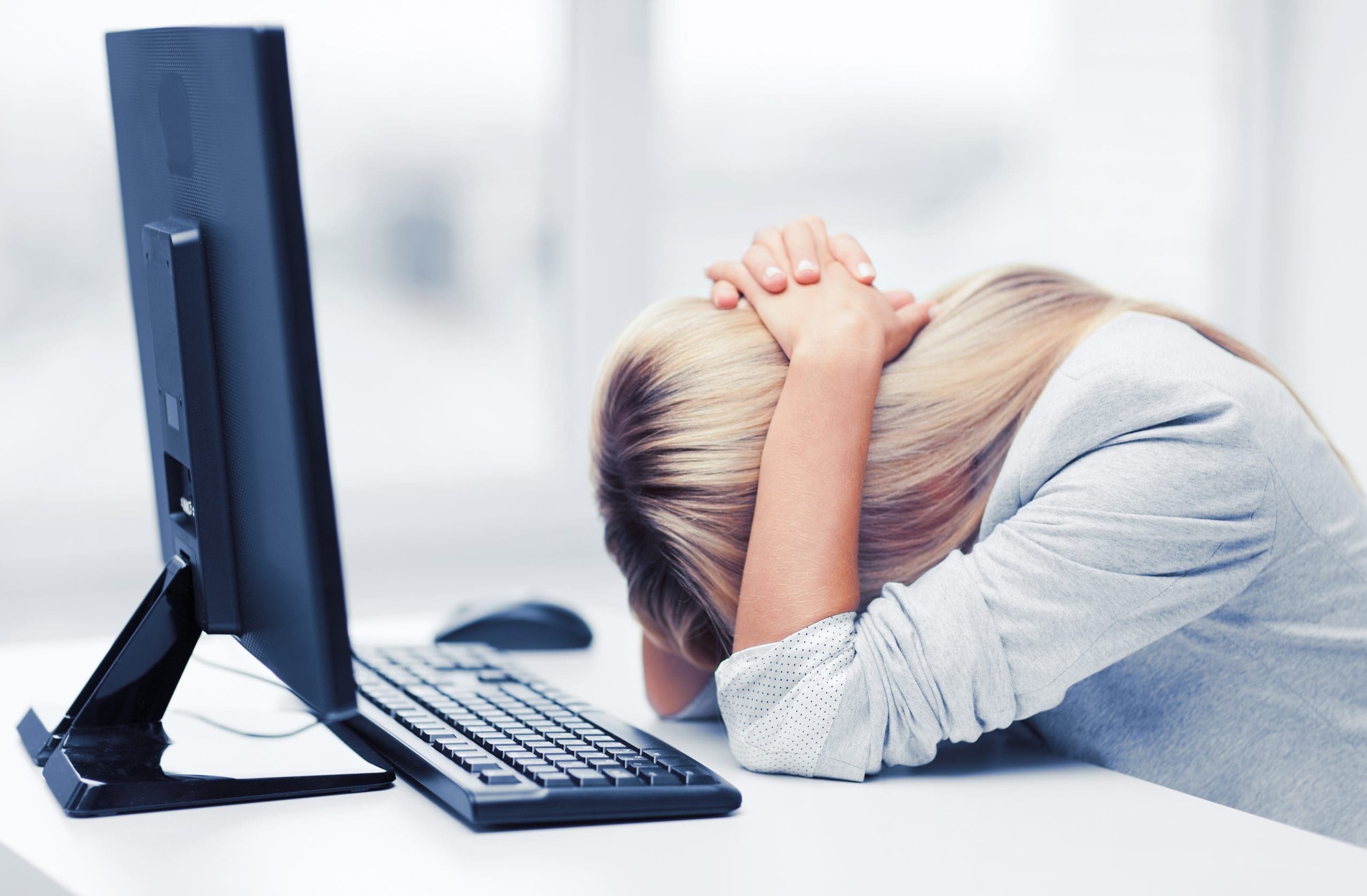 Woman with her head down in front of her computer.