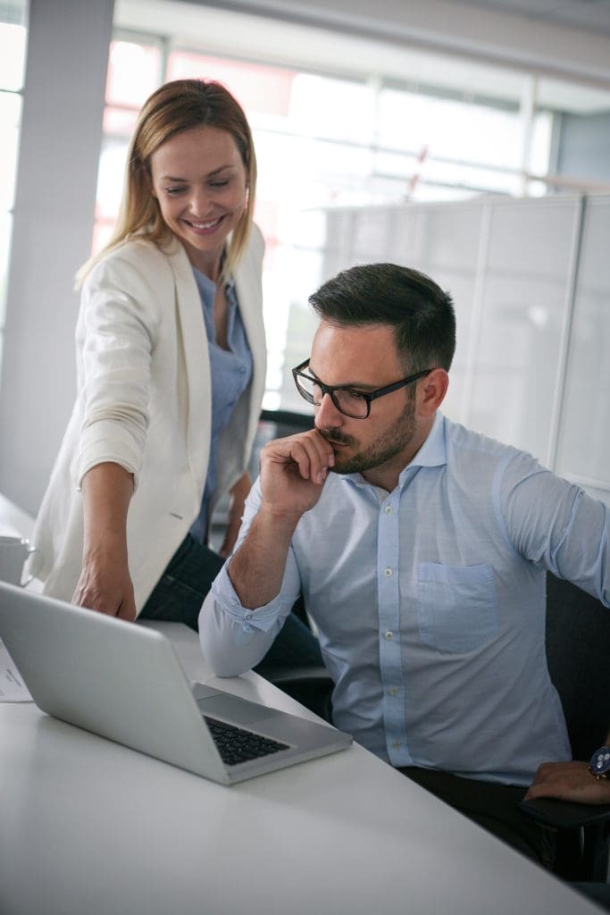 Business woman showing something to a colleague in laptop