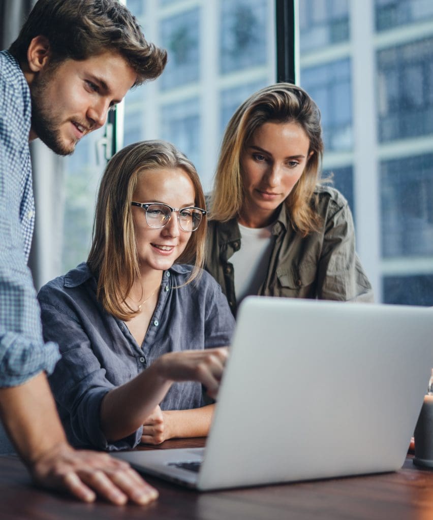 a trio of co-workers looking at a laptop
