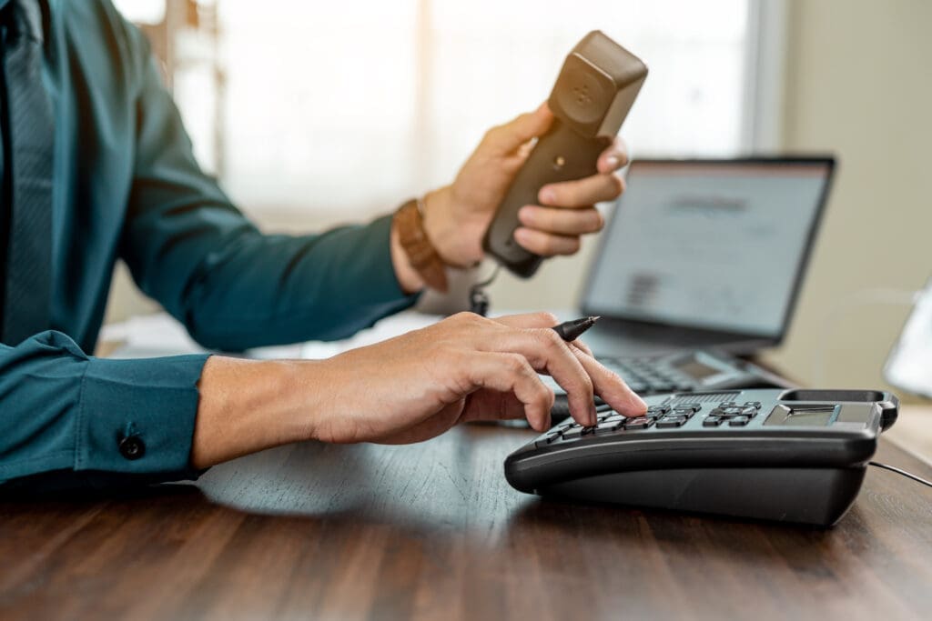 Businessman dialing VoIP phone in the office.